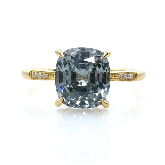18K YELLOW GOLD HANDCRAFTED "LAUREL CATHEDRAL" 4-PRONG ENGAGEMENT RING WITH 0.01TCW ROUND BRILLIANT DIAMOND ACCENTS AND MILGRAIN DETAIL FEATURING A 1.96CT LIGHT BLUE CUSHION CUT MONTANA SAPPHIRE BY ERIKA WINTERS.